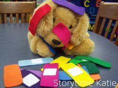 a teddy bear wearing a party hat sitting at a table with cut out pieces of felt