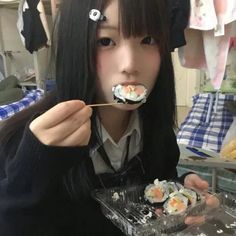 a woman eating sushi with chopsticks in her mouth