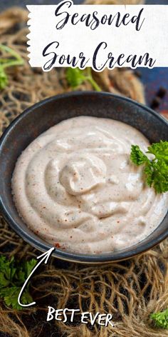 a bowl filled with white sauce and garnished with parsley on the side