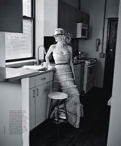 a woman standing in a kitchen next to a counter with a coffee cup on it