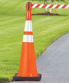 an orange and white cone sitting on the side of a road next to a tree