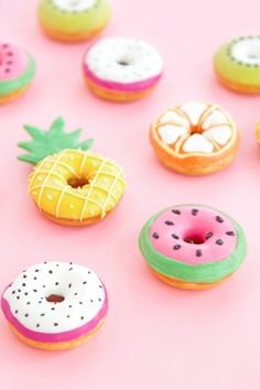 colorful donuts and pineapples on a pink background with white frosted icing