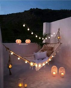 a hammock with lights hanging from it's sides and candles on the ground