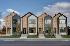 three story townhouses on the corner of a street with grass and trees in front of them