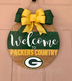 a green bay packers welcome sign hangs on the front door of a house with a yellow bow