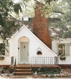 a white house with green shutters on the front and stairs leading up to it