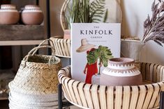 a book sitting on top of a table next to baskets filled with plants and potted plants