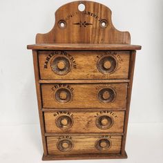 an old wooden drawer with knobs and holes on the front, sitting against a white wall