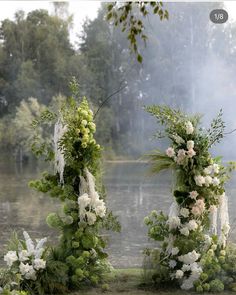 an outdoor ceremony setup with white flowers and greenery on the ground next to water