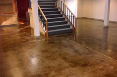 an empty room with concrete floors and stairs