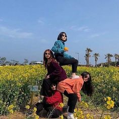 four people are standing in a field with yellow flowers and one person is holding an orange