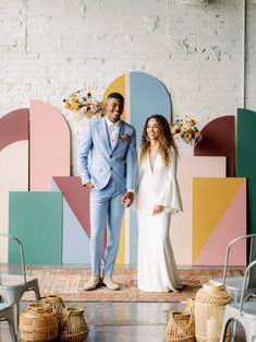 a man and woman standing next to each other in front of a wall with geometric shapes