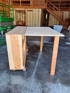 a table made out of plywood with wheels on the floor in a building under construction