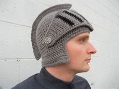 a man wearing a gray crocheted hat with black stripes and a button on the side