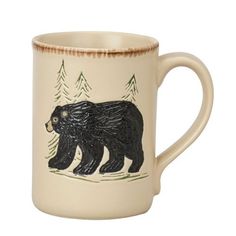 a coffee mug with a bear on it's side and pine trees in the background