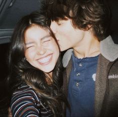 a young man and woman are kissing in the back seat of a car, with their eyes closed