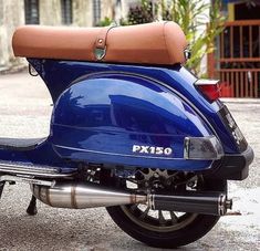 a blue scooter parked on the street with a brown seat and back rest