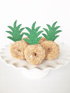 two donuts with pineapples on top in a white bowl and green glitter