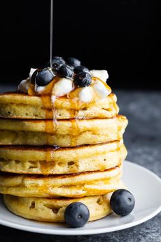 a stack of pancakes topped with blueberries and syrup