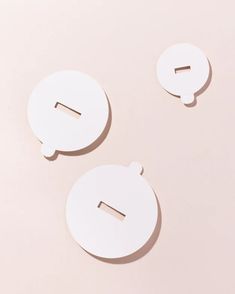 two white paper circles with holes in the middle on a light pink background, one has a hole for an object to cut out