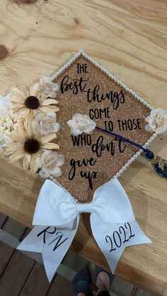 a decorated graduation cap with flowers on the table next to someone's name and date