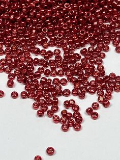 red seed beads are scattered on a white surface