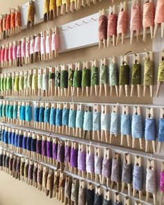 several rows of spools of thread hang on the wall next to each other