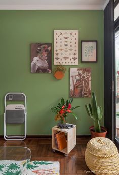 a living room with green walls and pictures on the wall, including a potted plant