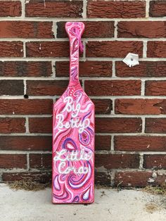 a pink and purple bottle with the word boo boo on it next to a brick wall