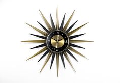 a black and gold clock with numbers on it's face in the shape of a star