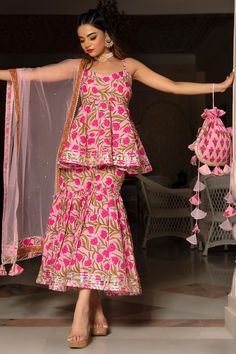 Make an everlasting, eternal impression at any upcoming festive occasion in this pink cotton shararta set with beautiful soft net dupatta comparising with beautiful fabric lace boarder.The sharara set features an overall hand block print, sweetheart neckline round , and magzi gotta detailing at neckline and allover sharara set .. The pink soft net dupatta comes with an overall hand block print fabric border and tassel detailing around the edges. this is a great pick for the festive season! PRODU Floral Print Sharara, Sharara Designs, Potli Bag, Indian Dresses Traditional, Traditional Indian Outfits, Trendy Dress Outfits, Kurta Designs Women, Party Wear Indian Dresses, Sharara Set