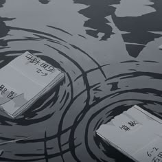 two boxes floating on top of a body of water next to an object in the water