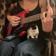 a woman playing guitar with a cat sitting on her lap