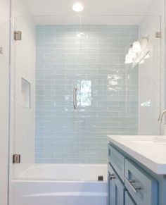 a bathroom with blue cabinets and a white bathtub next to a walk in shower