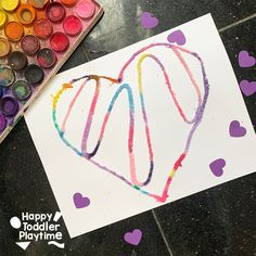 a heart drawn with colored crayons on a piece of paper next to some paint