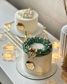 two white cakes sitting on top of a table covered in frosting and gold decorations