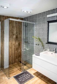 a bathroom with a sink, mirror and shower stall in the middle of it's wood flooring