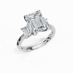 an emerald - cut diamond ring with three baguets on the shoulders, set in 18k white gold