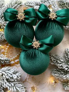 three green christmas ornaments with bows on them