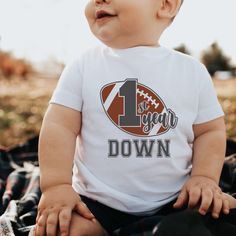 a baby sitting on top of a blanket wearing a football shirt