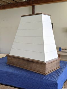 a white and brown object sitting on top of a blue mattress in a room with wooden beams