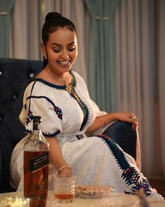 a woman sitting in a chair next to a bottle of liquor