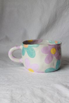 a flowered cup sitting on top of a white table