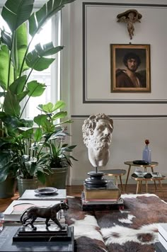 a living room filled with furniture and a large plant in front of a painting on the wall