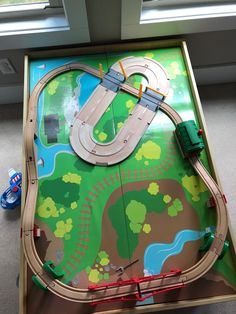 a toy train set sitting on top of a wooden table in front of a window