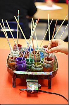 there are many pots with sticks sticking out of them on the table in front of people