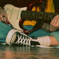 a person sitting on the floor playing an electric guitar