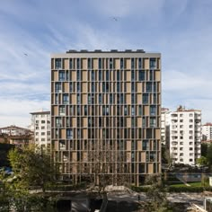 a large building with lots of windows next to trees and buildings on the other side