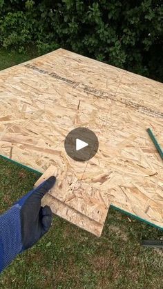 a person holding a tool in front of a wooden table that has been built into the ground