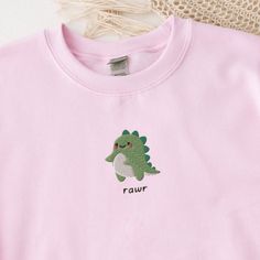 Rawr Dinosaur Sweatshirt, Embroidered Dino Crewneck Sweater, Cute Dinosaur Shirt, Baby Dinosaur Sweatshirt, Cute Embroidered Sweatshirt This embroidered dinosaur crewneck sweatshirt is everything. Perfect to show your love for baby dinosaurs! Please let me know if you would like extended sizing (3X-5X), I have certain color and size combinations available! ✨ 50% cotton, 50% polyester ✨ Pre-shrunk ✨ Classic fit Care: Machine wash: warm (max 40C or 105F) Tumble dry: low Do not iron directly on the Dinosaur Crewneck, Dino Sweater, Embroidered Dinosaur, Embroidered Baby Clothes, Dinosaur Sweatshirt, Birthday Presents For Friends, Baby Dinosaur, Dinosaur Shirt, Embroidery Stitches Tutorial